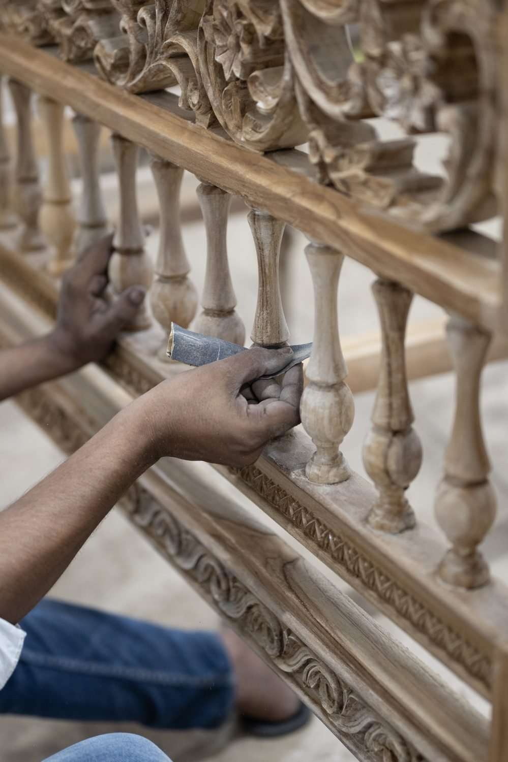 Hands sanding the turned spindles of a carved frame